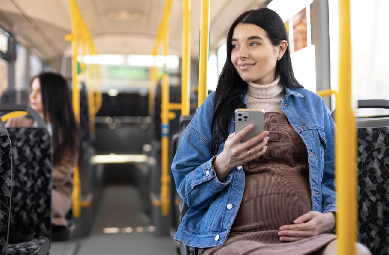 A pregnant woman sitting safely inside a modern bus.